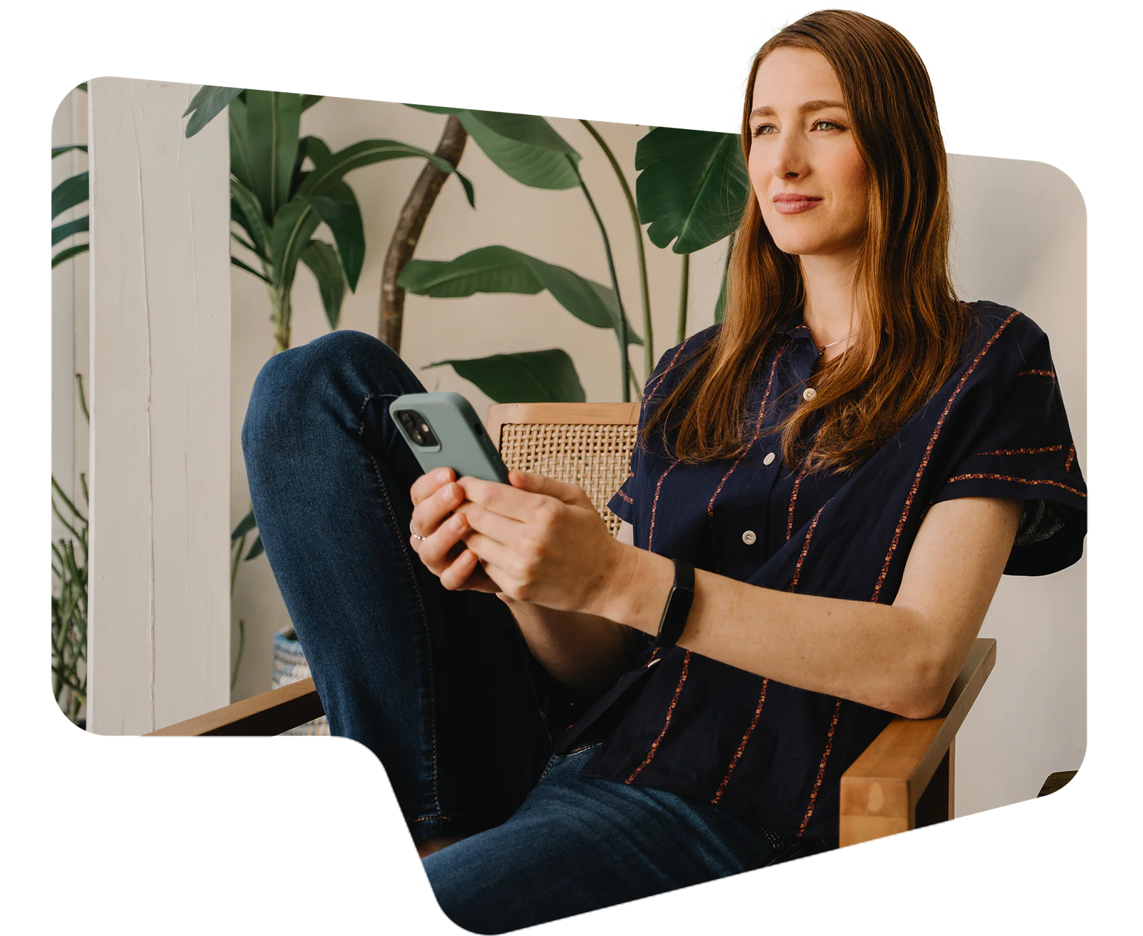 Woman sitting on patio with a phone, next to a laptop and plants
